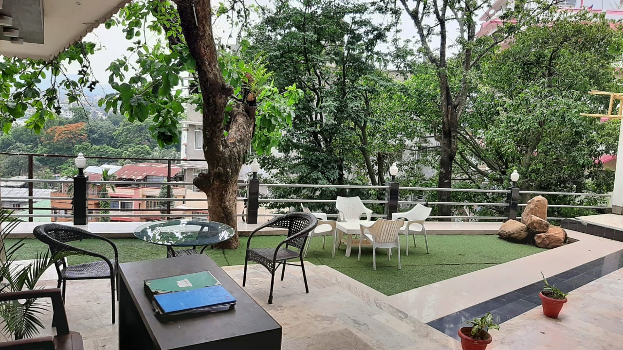 Outdoor lounge with chairs set around old trees, overlooking the hillside